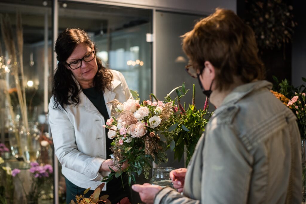 Kauppias ojentaa asiakkaalle kukkakimppua