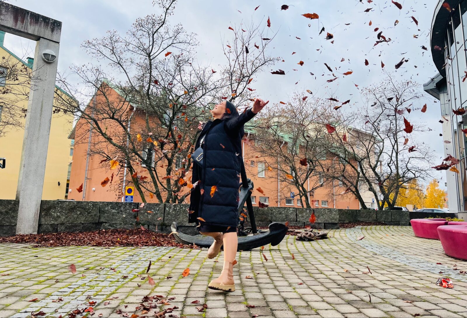 Ihminen heittää lehtiä ilmaan kaupungin keskustassa