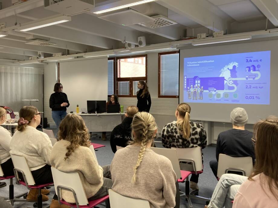 Ihmisiä luokkahuoneessa seuraamassa esitystä