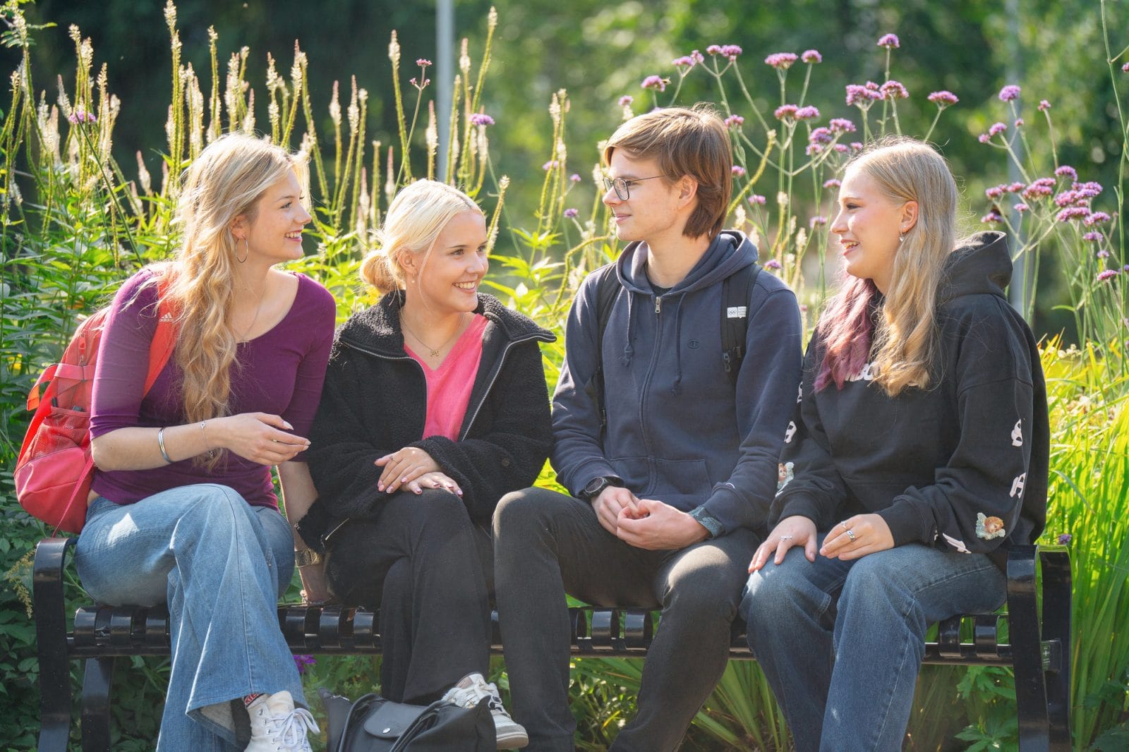 nuoria istumassa puiston penkillä