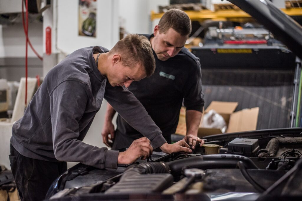 Kaksi työntekijää korjaa auton moottoria